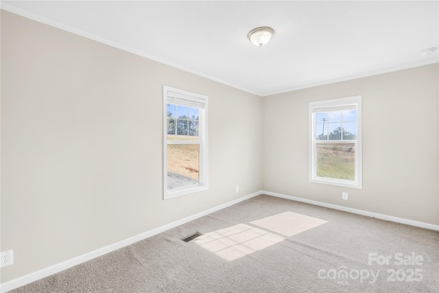 carpeted empty room with baseboards, visible vents, and ornamental molding