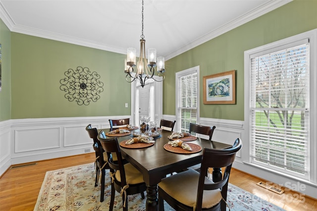 dining area featuring visible vents, a chandelier, light wood-style floors, and crown molding