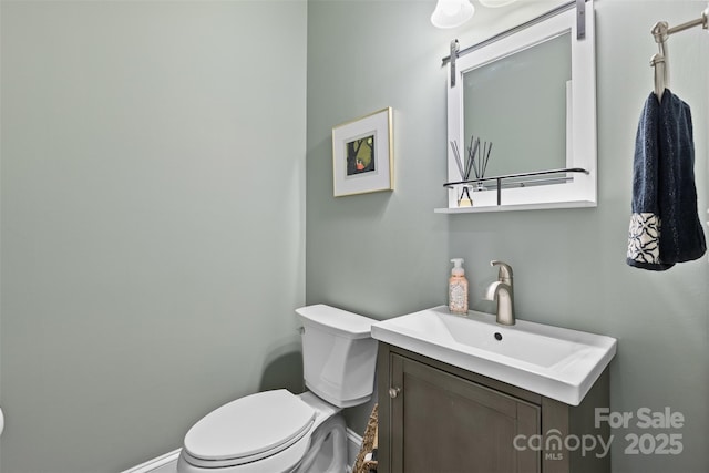 bathroom featuring baseboards, toilet, and vanity