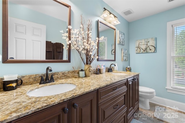 bathroom featuring double vanity, visible vents, toilet, and a sink