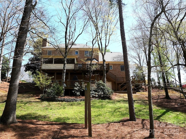 rear view of property featuring a yard, stairs, and a wooden deck