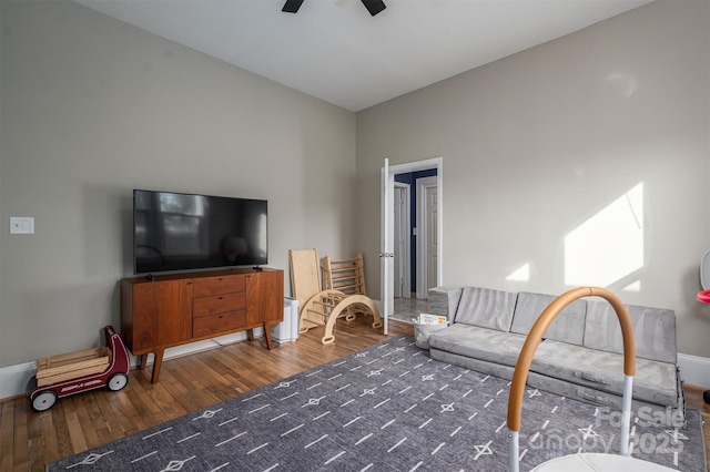 living area featuring baseboards, ceiling fan, and wood finished floors