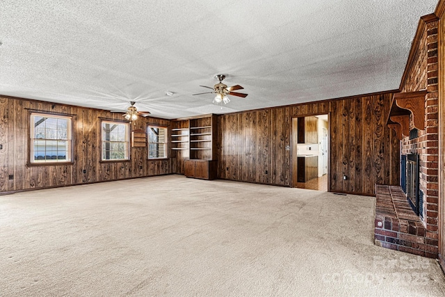 2 Honeysuckle Way, Granite Falls, NC 28630 - unfurnished living room with wood walls, a ceiling fan, a brick fireplace, a textured ceiling, and carpet floors