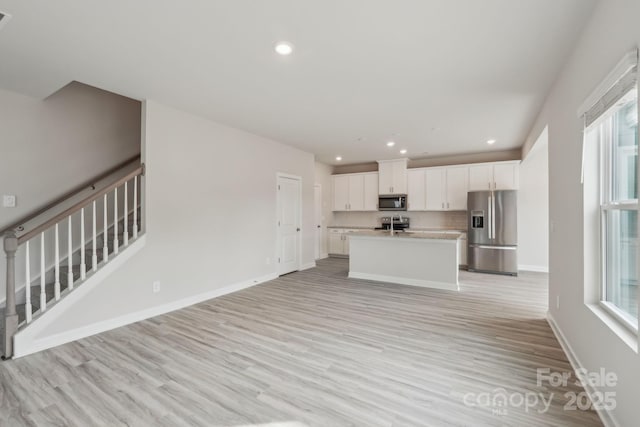 1305 31st St NE, Conover, NC 28613 - kitchen featuring light wood-type flooring, a center island with sink, plenty of natural light, white cabinets, and appliances with stainless steel finishes