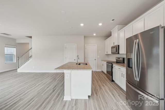 1305 31st St NE, Conover, NC 28613 - kitchen featuring light wood finished floors, a sink, stainless steel appliances, white cabinets, and a kitchen island with sink