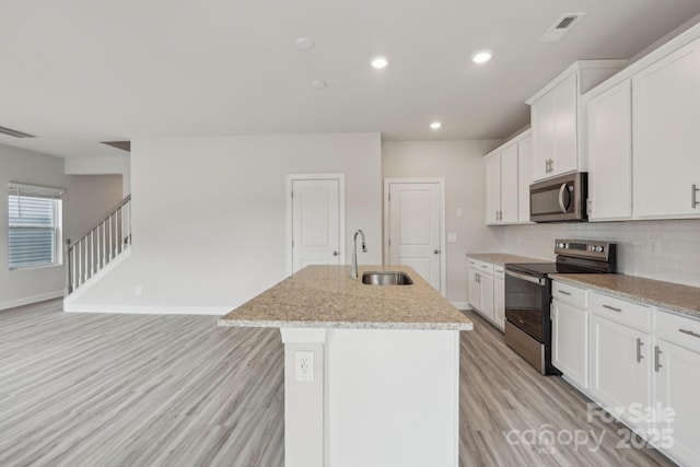 1305 31st St NE, Conover, NC 28613 - kitchen with light wood finished floors, an island with sink, a sink, visible vents, and appliances with stainless steel finishes