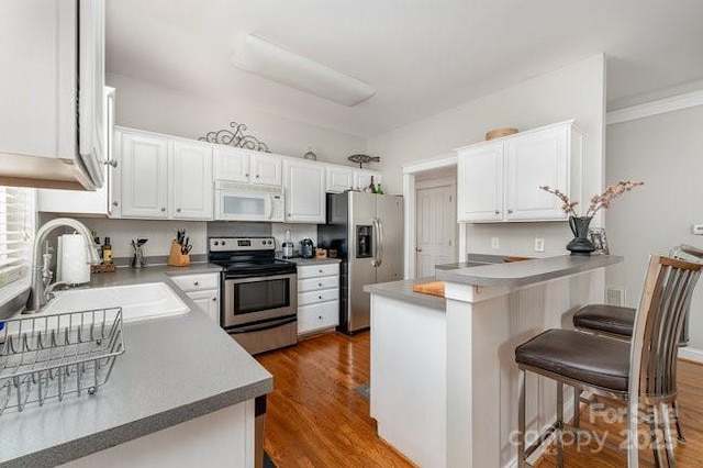 10802 Tradition View Dr, Charlotte, NC 28269 - kitchen with white cabinets, a peninsula, stainless steel appliances, a sink, and a breakfast bar area