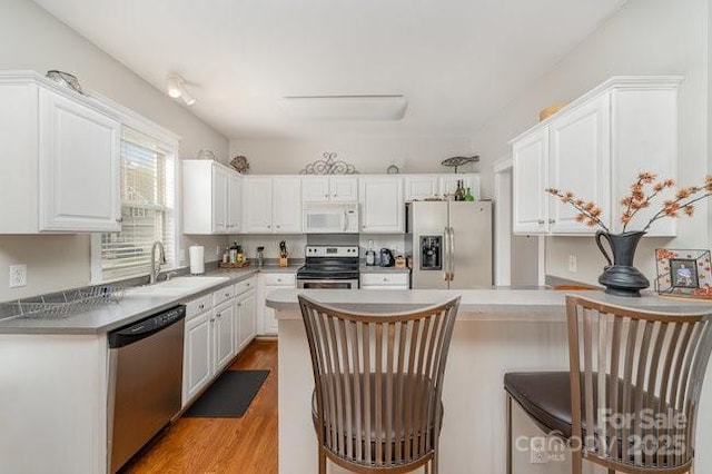 10802 Tradition View Dr, Charlotte, NC 28269 - kitchen with a sink, white cabinets, a peninsula, appliances with stainless steel finishes, and wood finished floors