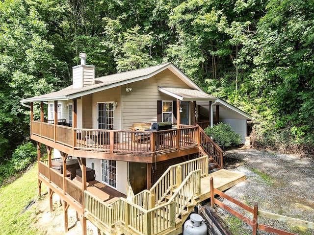 rear view of house with stairs, a chimney, and a wooden deck