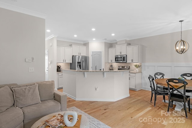 6021 Sweetbay Ln, Indian Land, SC 29707 - living area featuring a notable chandelier, ornamental molding, light wood-type flooring, and wainscoting