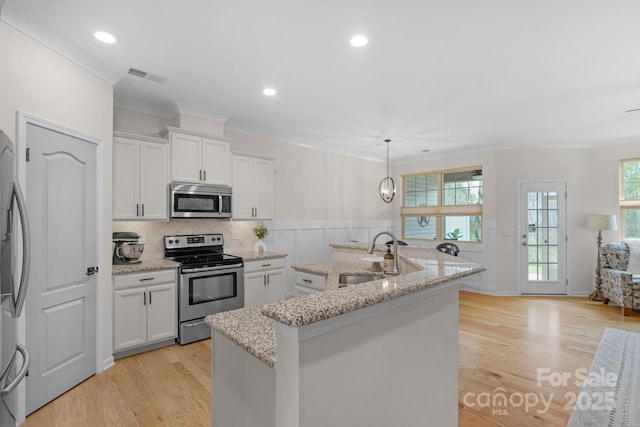 6021 Sweetbay Ln, Indian Land, SC 29707 - kitchen with stainless steel appliances, a center island with sink, a sink, light wood finished floors, and visible vents