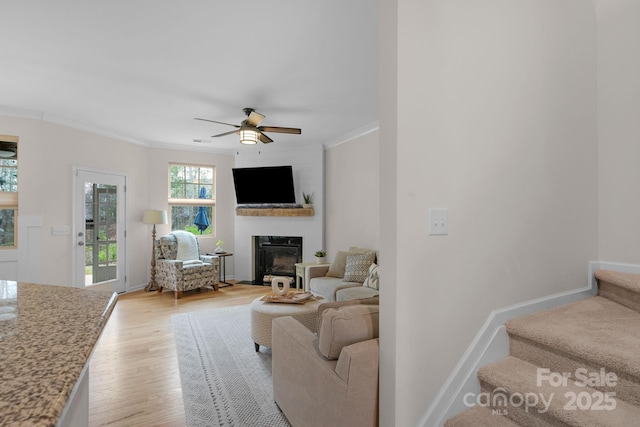 6021 Sweetbay Ln, Indian Land, SC 29707 - living area featuring light wood finished floors, stairs, ornamental molding, ceiling fan, and a glass covered fireplace