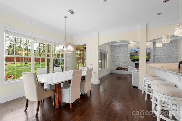 dining area featuring visible vents, crown molding, a chandelier, arched walkways, and dark wood-style floors