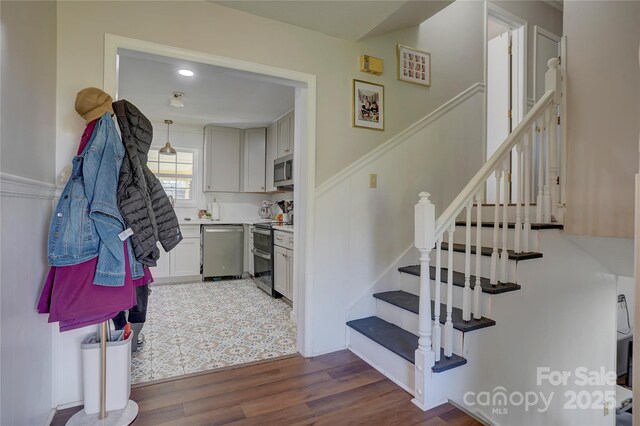 stairs featuring wainscoting and wood finished floors