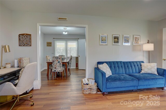 living area with visible vents, baseboards, and wood finished floors