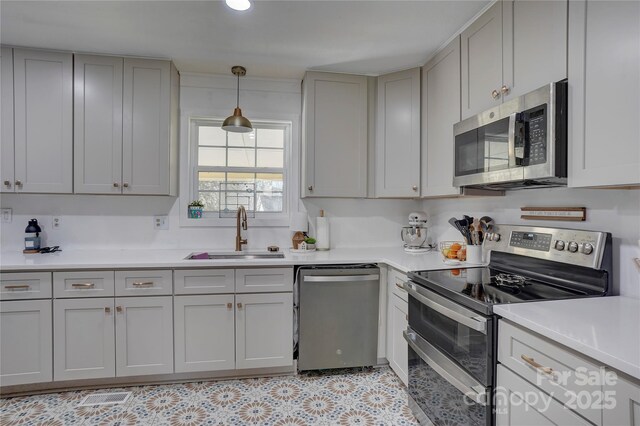 kitchen featuring a sink, gray cabinetry, light countertops, and appliances with stainless steel finishes