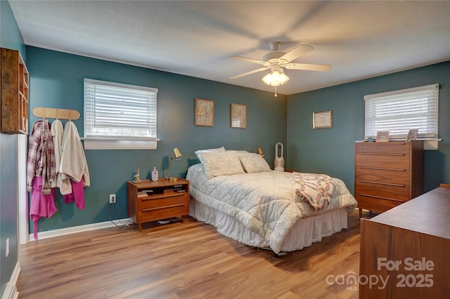 bedroom featuring multiple windows, wood finished floors, ceiling fan, and baseboards