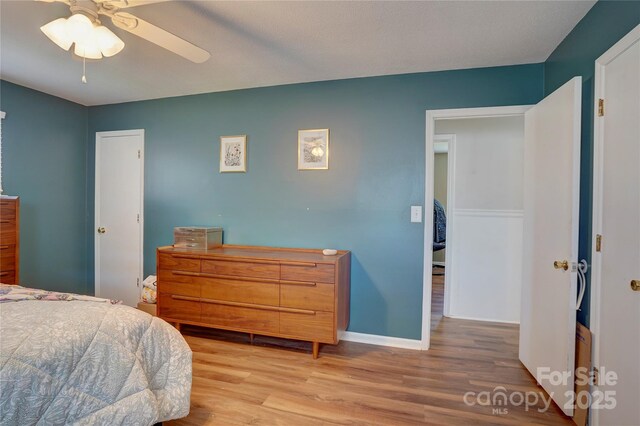 bedroom featuring baseboards, light wood-style floors, and a ceiling fan