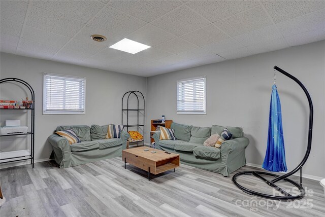 living room with baseboards, visible vents, wood finished floors, and plenty of natural light
