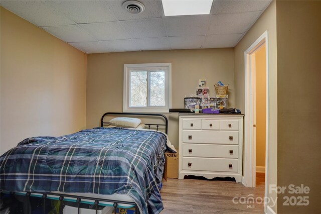 bedroom featuring visible vents, a drop ceiling, and wood finished floors