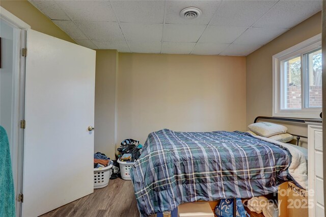 bedroom with visible vents, wood finished floors, and a drop ceiling