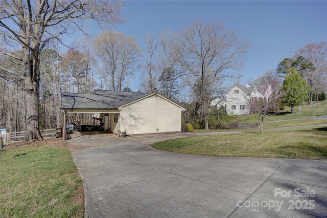 view of property exterior featuring driveway, fence, and a lawn