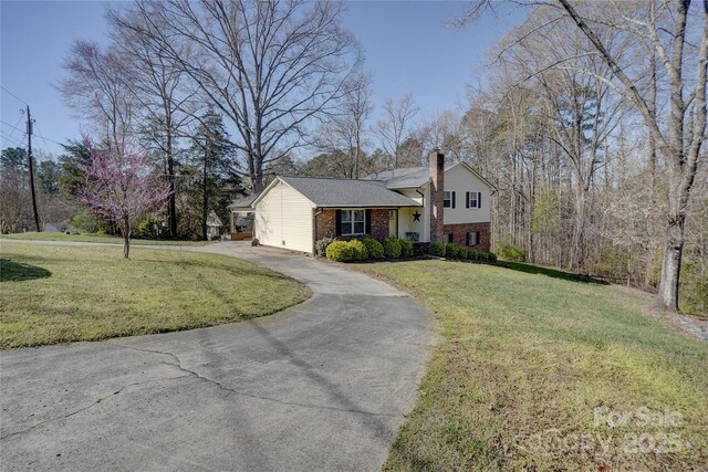tri-level home with a front yard, brick siding, concrete driveway, and a chimney