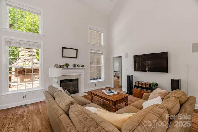 living room with high vaulted ceiling, baseboards, wood finished floors, and visible vents