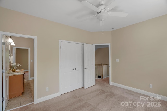 unfurnished bedroom featuring baseboards, light colored carpet, ceiling fan, and a closet