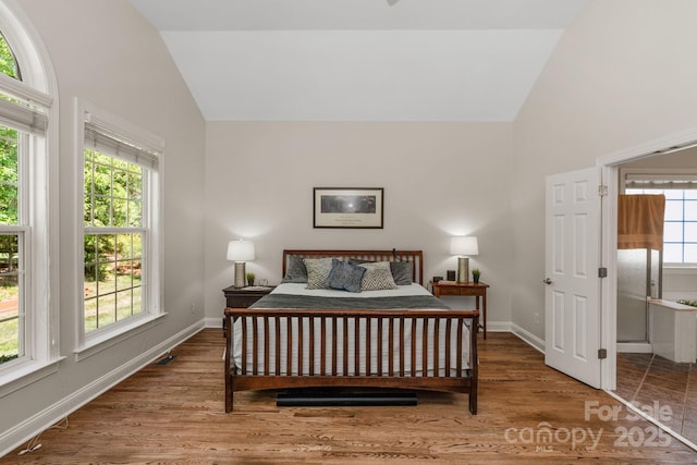 bedroom featuring baseboards, high vaulted ceiling, and wood finished floors