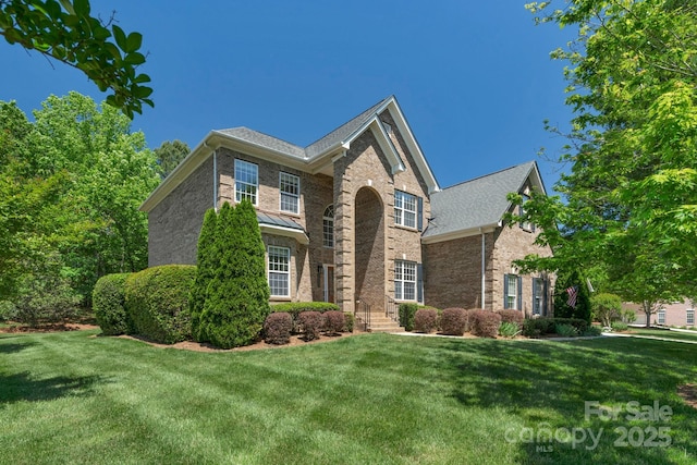 traditional-style house featuring brick siding and a front lawn