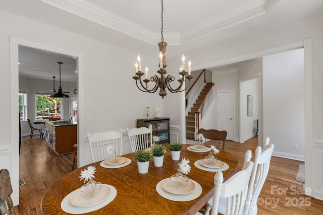 dining room featuring crown molding, stairs, a notable chandelier, and wood finished floors