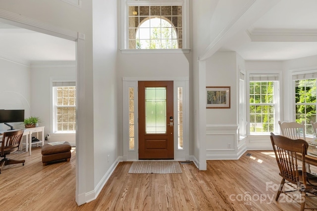 foyer featuring light wood-style floors, baseboards, and crown molding