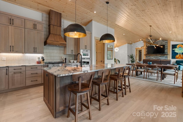 192 Lakeview Trl, Bryson City, NC 28713 - kitchen with custom range hood, wooden ceiling, light stone countertops, a center island with sink, and backsplash