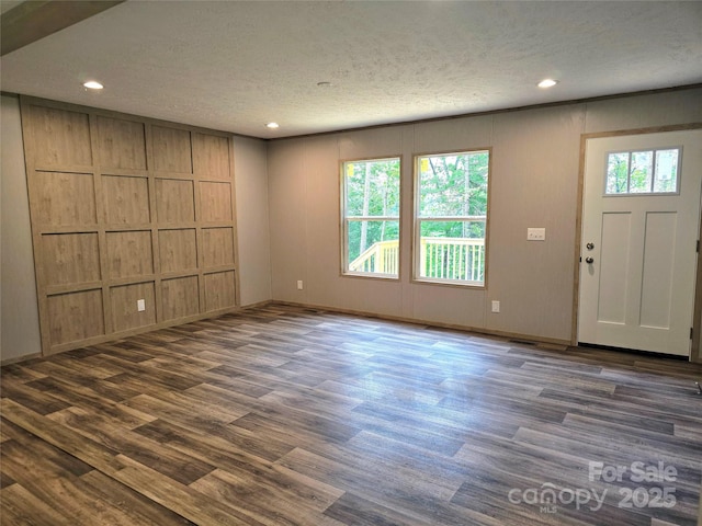 entrance foyer with a textured ceiling, dark wood-type flooring, recessed lighting, baseboards, and a decorative wall