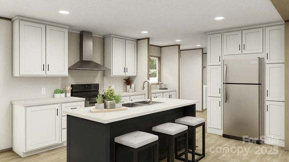 kitchen featuring freestanding refrigerator, wall chimney range hood, range, a sink, and light wood-style flooring