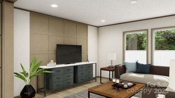 living area featuring light wood finished floors, a textured ceiling, recessed lighting, and a decorative wall