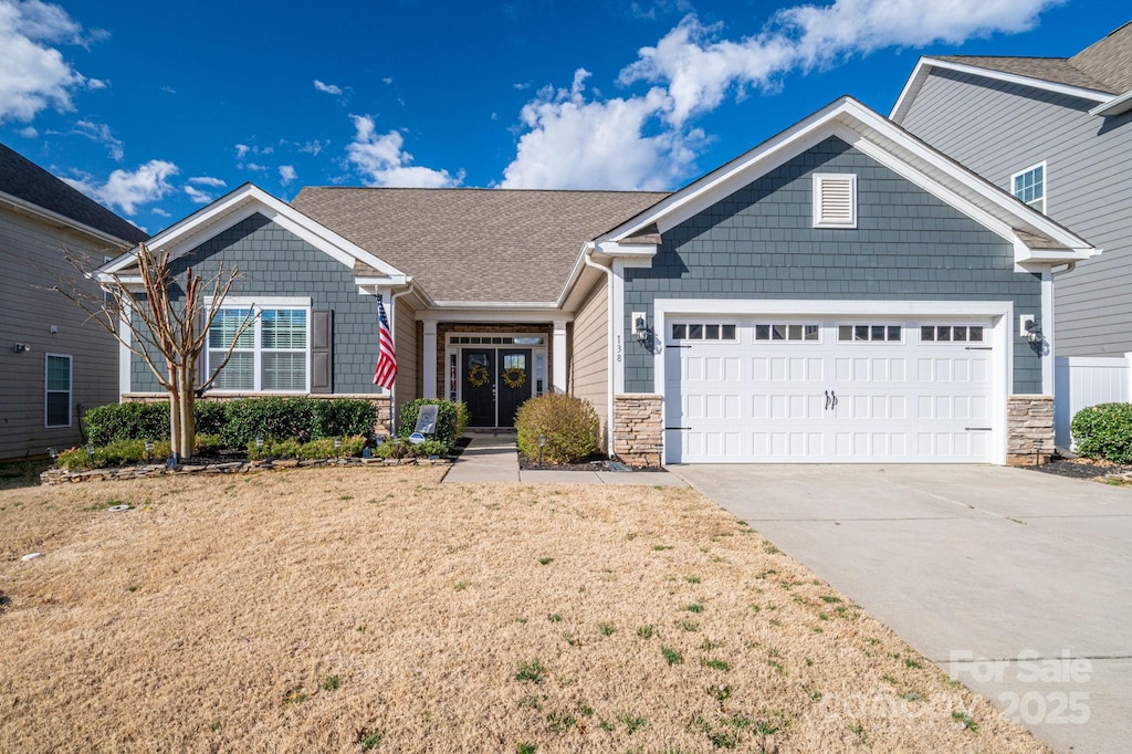 craftsman inspired home featuring concrete driveway, an attached garage, and stone siding