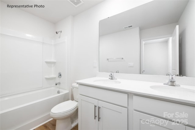 bathroom with toilet, a sink, visible vents, and double vanity