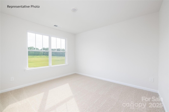 spare room featuring light carpet, visible vents, and baseboards