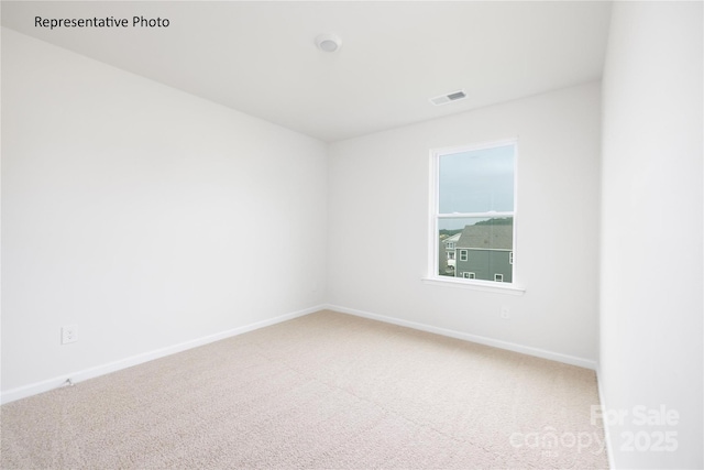 spare room featuring carpet floors, visible vents, and baseboards