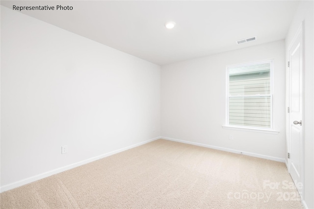 empty room with visible vents, baseboards, and light carpet