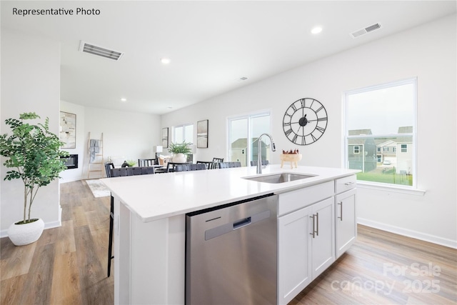 kitchen with white cabinets, stainless steel dishwasher, visible vents, and a sink