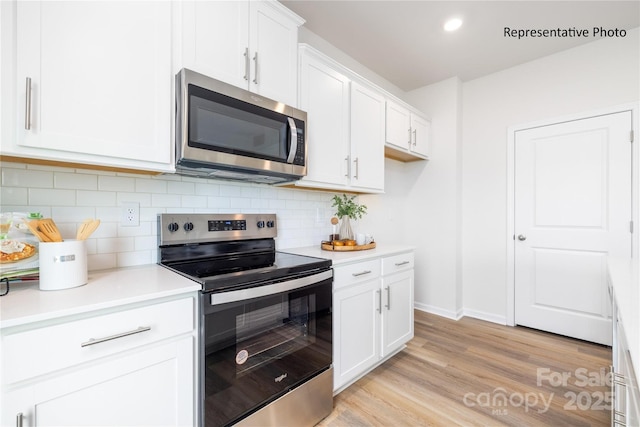 kitchen featuring white cabinets, stainless steel appliances, light wood-style flooring, backsplash, and light countertops