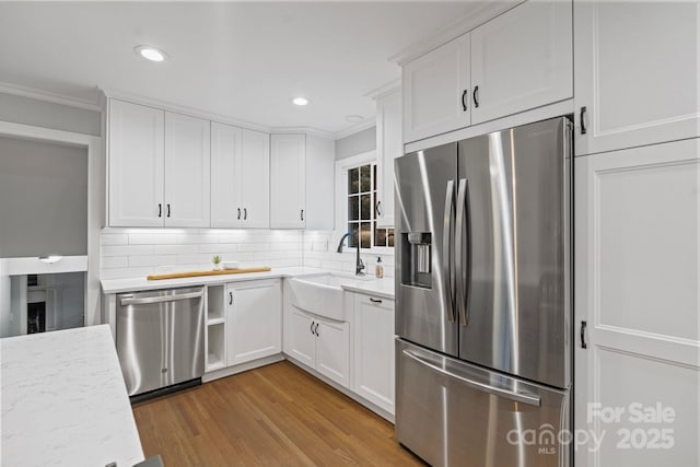 3808 Severn Ave, Charlotte, NC 28210 - kitchen featuring tasteful backsplash, crown molding, light wood finished floors, white cabinets, and appliances with stainless steel finishes