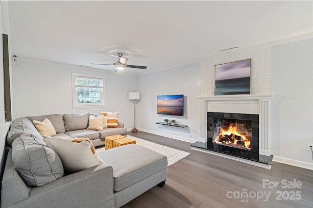 3808 Severn Ave, Charlotte, NC 28210 - living room featuring a warm lit fireplace, wood finished floors, ornamental molding, and a ceiling fan