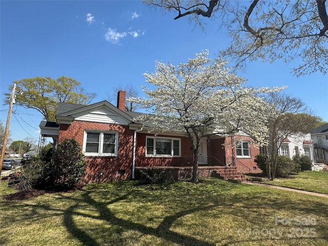 view of front of property with crawl space, a chimney, a front yard, and brick siding