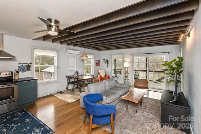 living area featuring beam ceiling, ceiling fan, wood finished floors, and a wall mounted air conditioner