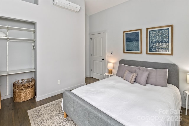 bedroom featuring baseboards, wood finished floors, and a wall mounted air conditioner
