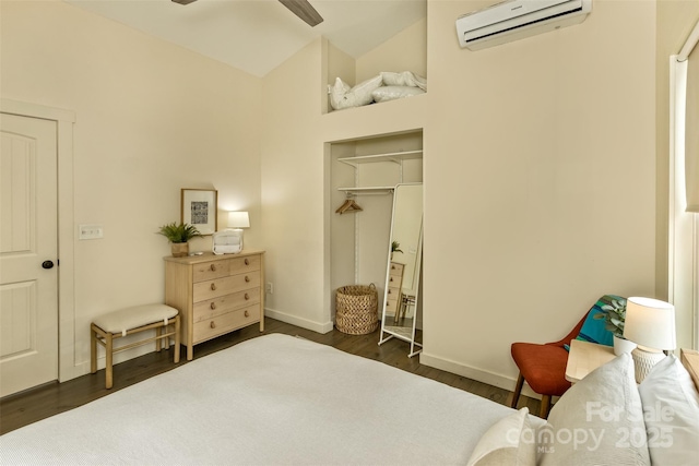 bedroom with a closet, baseboards, a wall mounted AC, dark wood-style floors, and lofted ceiling